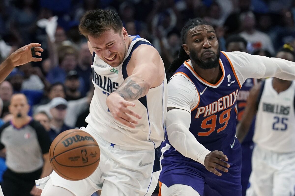 Dallas Mavericks guard Luka Doncic, left, and Phoenix Suns forward Jae Crowder (99) battle for a loose ball during the second half of Game 3 of an NBA basketball second-round playoff series, Friday, May 6, 2022, in Dallas. (AP Photo/Tony Gutierrez)