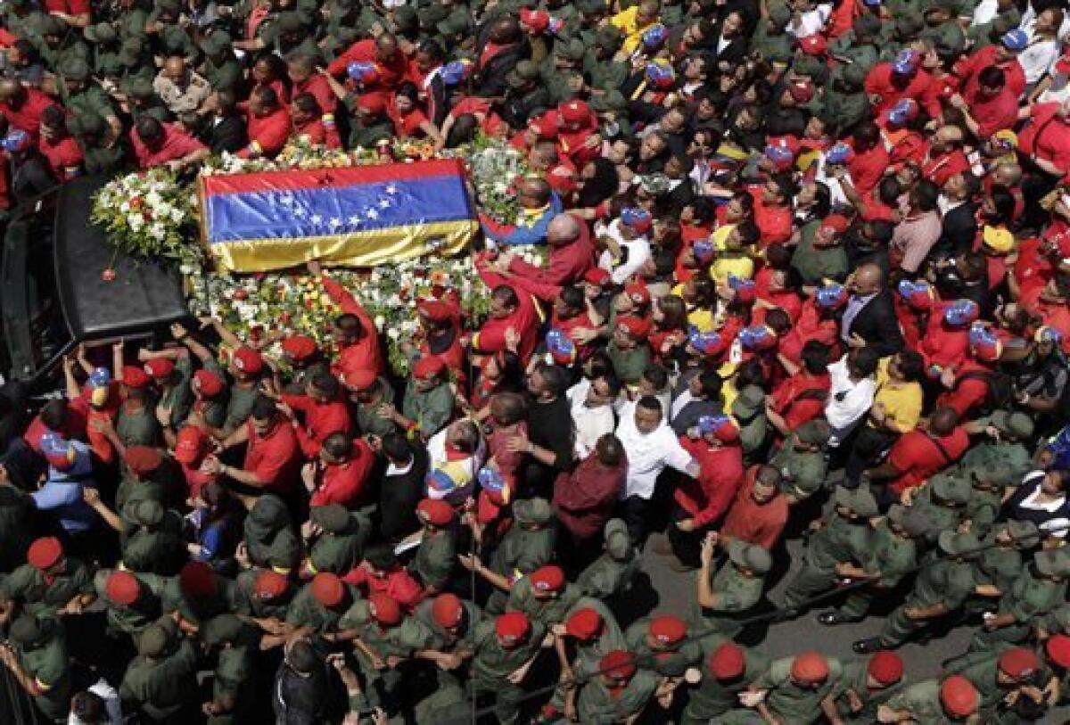 People walk alongside the flag-draped coffin containing the body of Venezuela's late President Hugo Chavez from the hospital where he died, to a military academy where it will remain until his funeral in Caracas, Venezuela, Wednesday, March 6, 2013. Seven days of mourning were declared, all schools were suspended for the week and friendly heads of state were expected for an elaborate funeral Friday. (AP Photo/Ariana Cubillos)