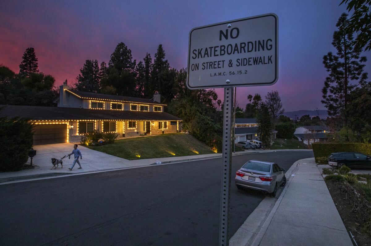 A man walks a dog on a sidewalk.