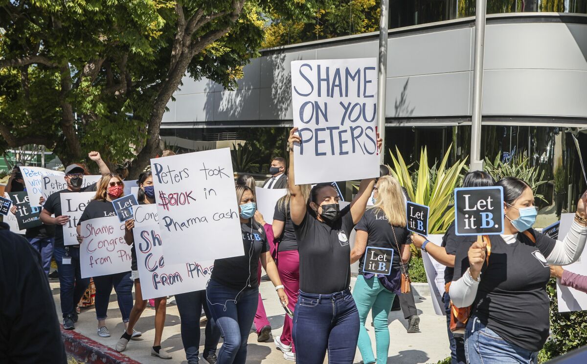 A group of advocates protest against Congressman Scott Peters' vote.