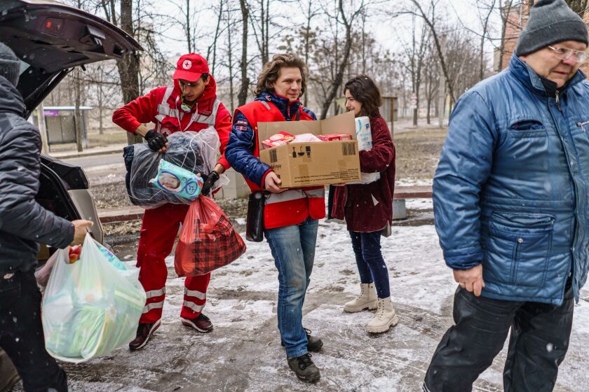 KHARKIV, UKRAINE -- MARCH 27, 2022: Alexander Lebediev, center and other Red Cross workers deliver supplies to residents who have been cut off from humanitarian aid and are hiding in shelters in the outskirts of Kharkiv, Ukraine, Sunday, March 27, 2022. (MARCUS YAM / LOS ANGELES TIMES)