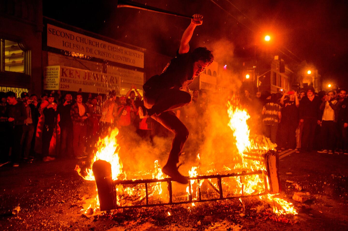 A man jumps over a burning couch in San Francisco's Mission district after the San Francisco Giants defeated the Kansas City Royals to win the World Series.