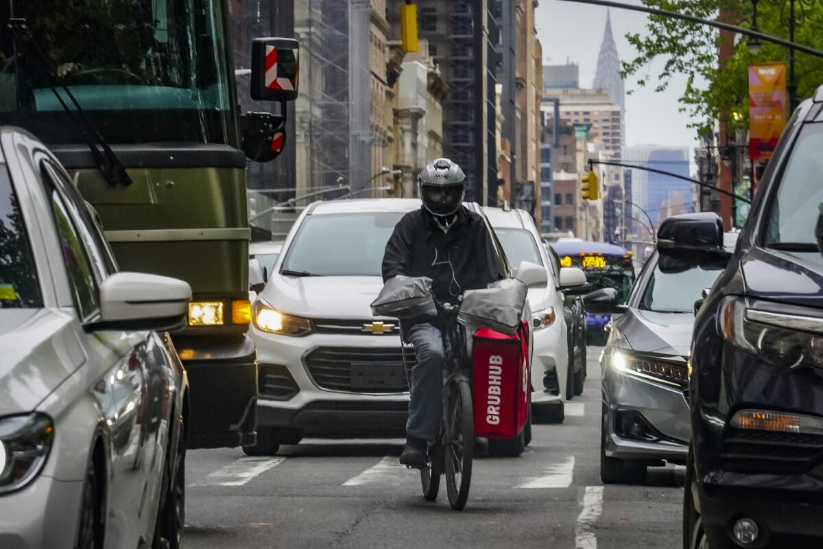 A food delivery worker rides through traffic.