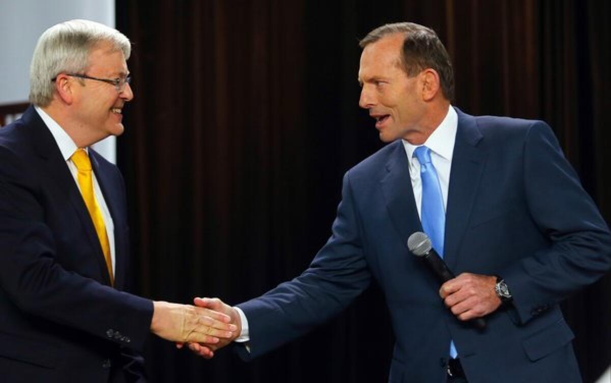 Australian opposition leader Tony Abbott, right, greets incumbent Prime Minister Kevin Rudd at the start of a people's forum in Brisbane last month. Abbott's Liberal-National conservative coalition is tipped to win a clear majority of seats in Saturday's parliamentary voting, propelling the party leader into the prime minister's office.
