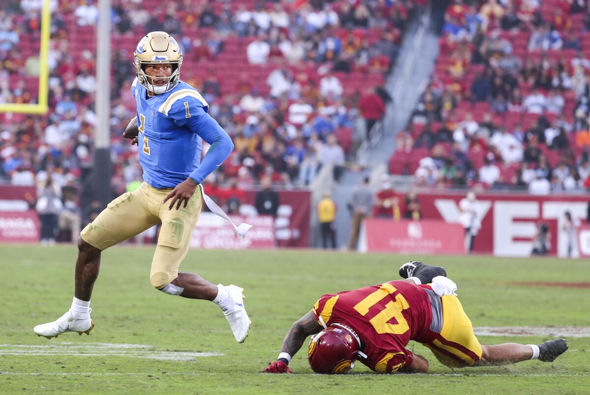 UCLA quarterback Dorian Thompson-Robinson, left, escapes a tackle attempt by USC cornerback Jayden Williams.