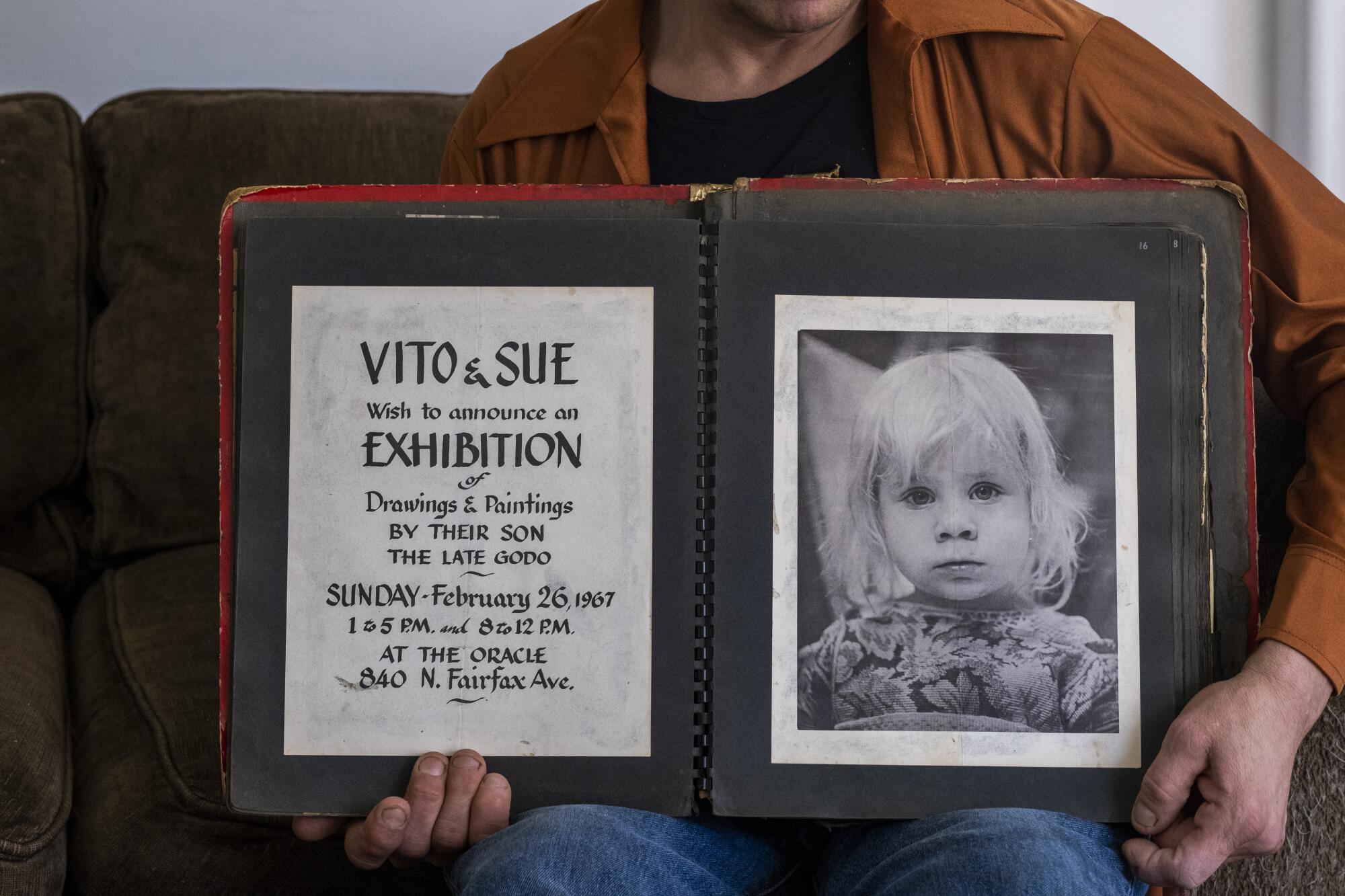 A person holds open a photo album with a picture of a blond child and an announcement.
