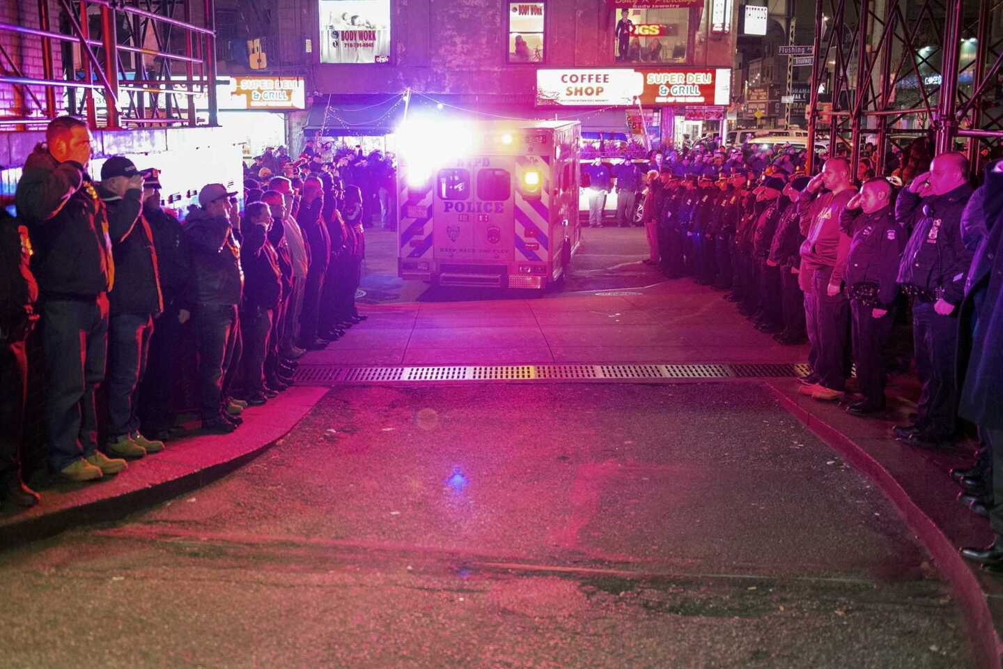 Police officers salute as vehicles containing the bodies of two New York Police officers who were shot dead drive by in the Brooklyn borough of New York