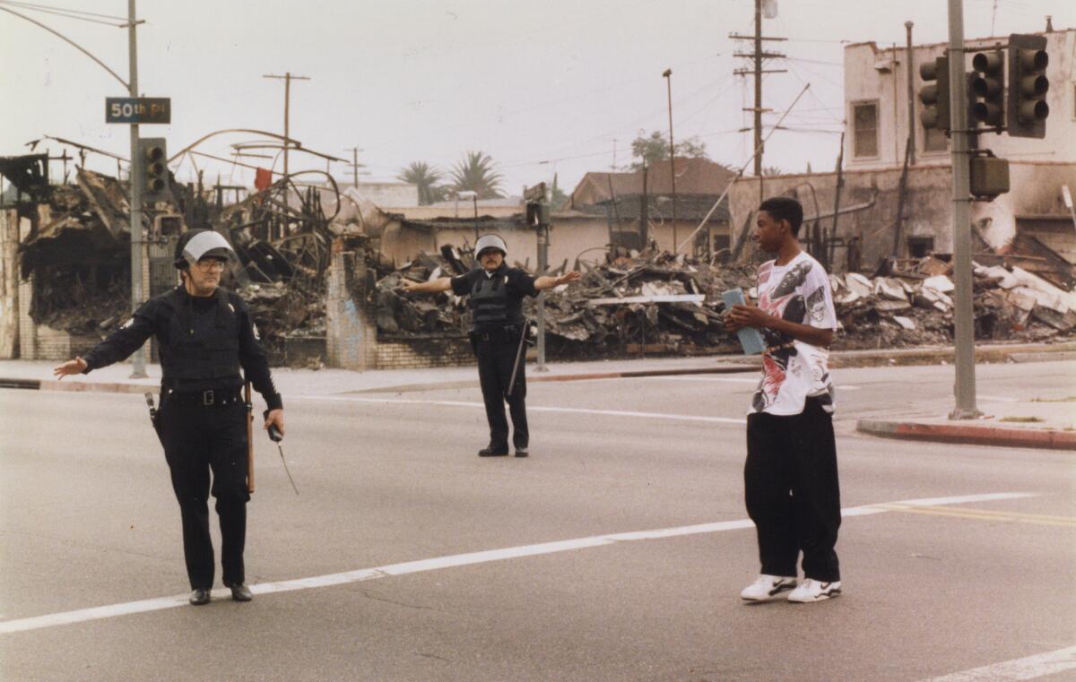 LAPD officers act as crossing guards at 50th Place and Vermont Avenue on May 4, 1992 for a student on his way to Audubon Junior High School, one of the campuses closed by the violence.