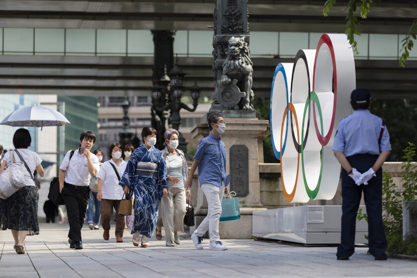 People walk by the Olympic rings installed by the Nihonbashi bridge in Tokyo.