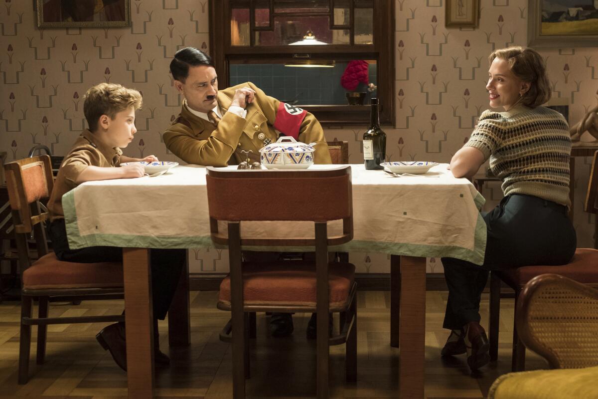 This image released by Fox Searchlight Pictures shows, from left, Roman Griffin Davis, Taika Waititi and Scarlett Johansson in a scene from the WWII satirical film "Jojo Rabbit."