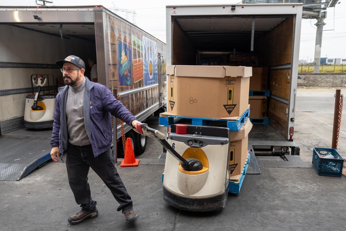 A man moves pallets of produce from his truck at Food Forward Produce Pit Stop.