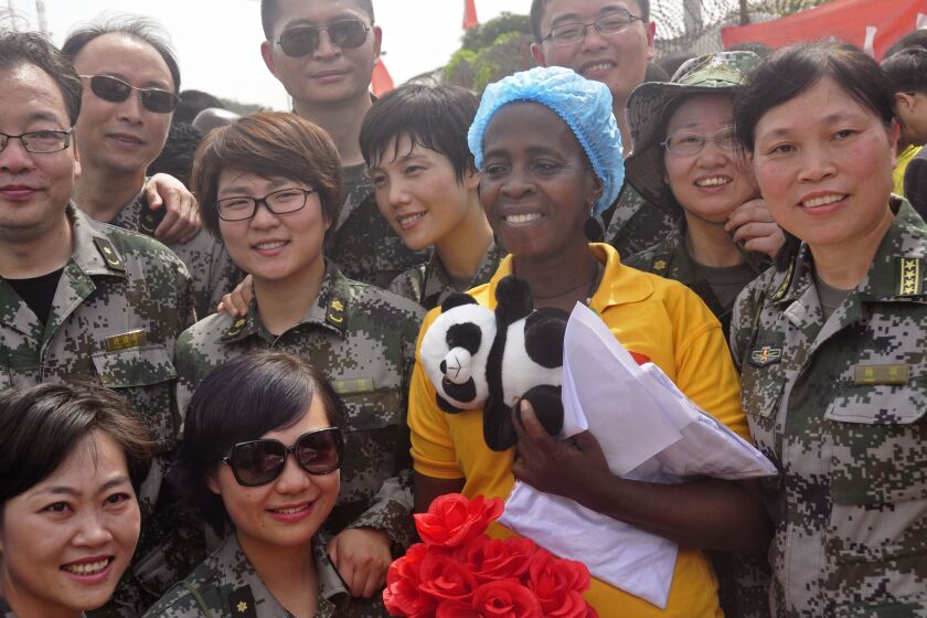 Ebola patient Beatrice Yardolo, center, is surrounded by Chinese military health workers as she leaves the Chinese Ebola treatment center were she was treated on the outskirts of Monrovia, Liberia, on March 5.