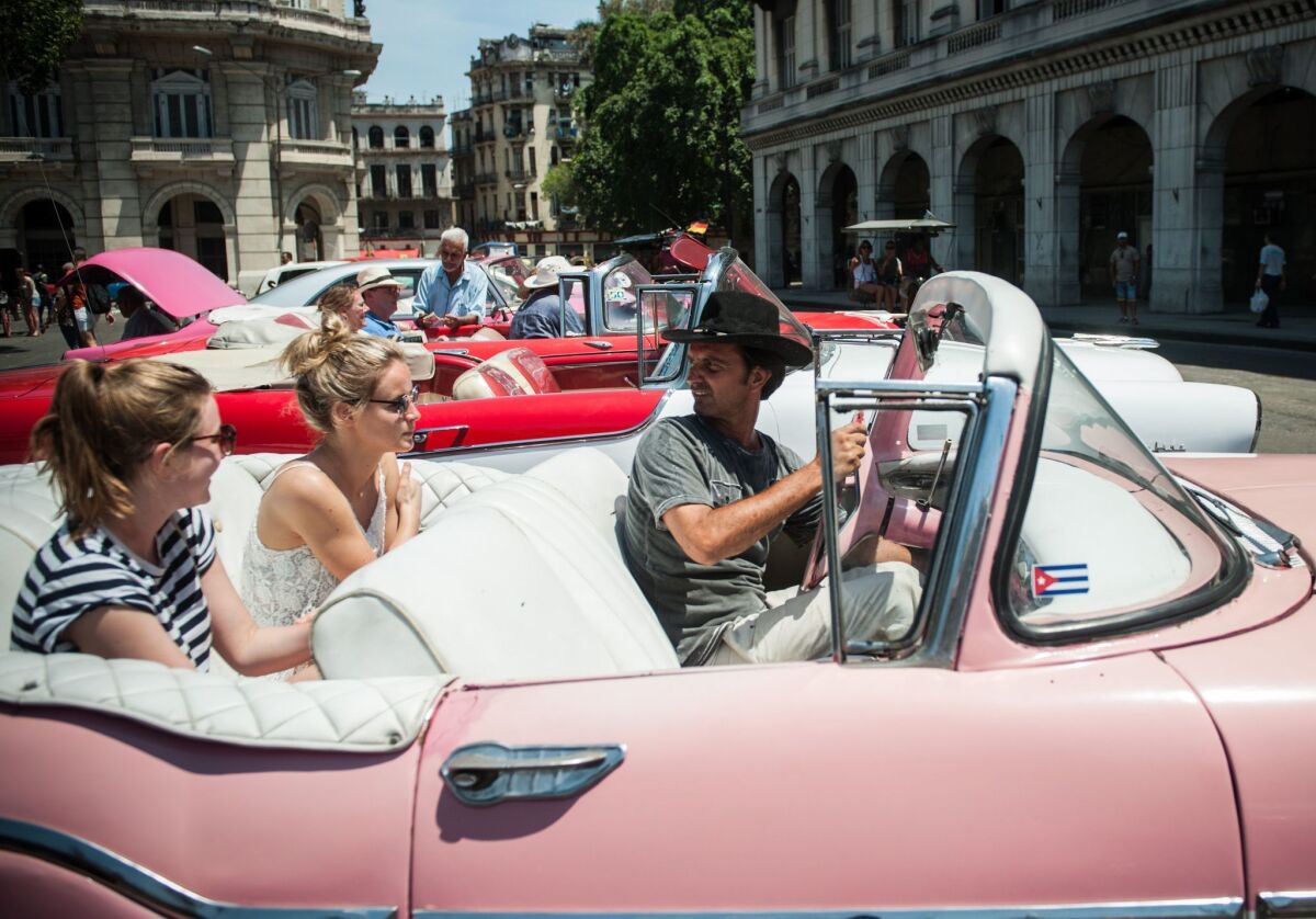 Tourists from the United States sit in a vintage American car in Havana, on April 6, 2015. With travel restrictions easing, online searches for travel to Cuba from the U.S. have jumped.
