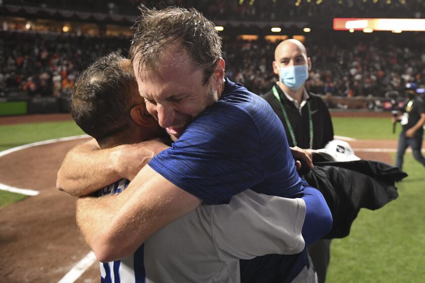 San Francisco, CA - October 14: Los Angeles Dodgers' Max Scherzer, right, hugs manager Dave Roberts after game five of the 2021 National League Division Series against the San Francisco Giants at Oracle Park on Thursday, Oct. 14, 2021 in San Francisco, CA. The Dodgers won 2-1. (Wally Skalij / Los Angeles Times)