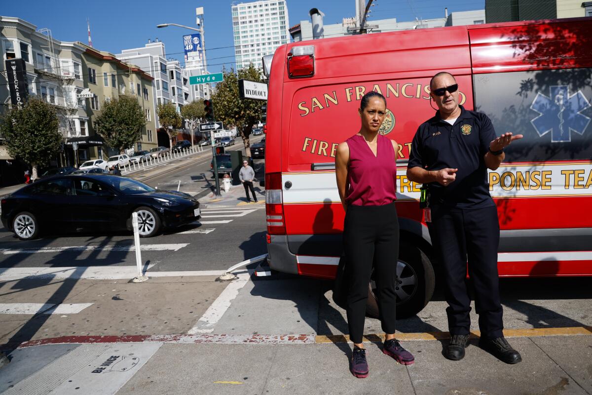 A woman stands beside a firefighter next to a fire department emergency vehicle