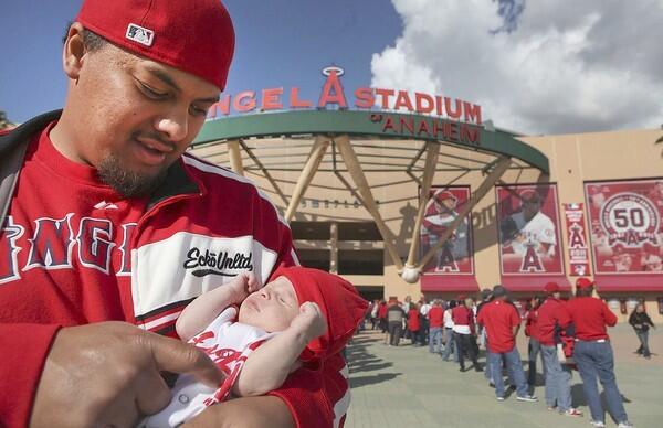 Angels fan J.R. Masitalo holds his three-week-old son Kingston as the family waits in line to enter Angels Stadium prior to the Angels' home opener against the Toronto Blue Jays on Friday.
