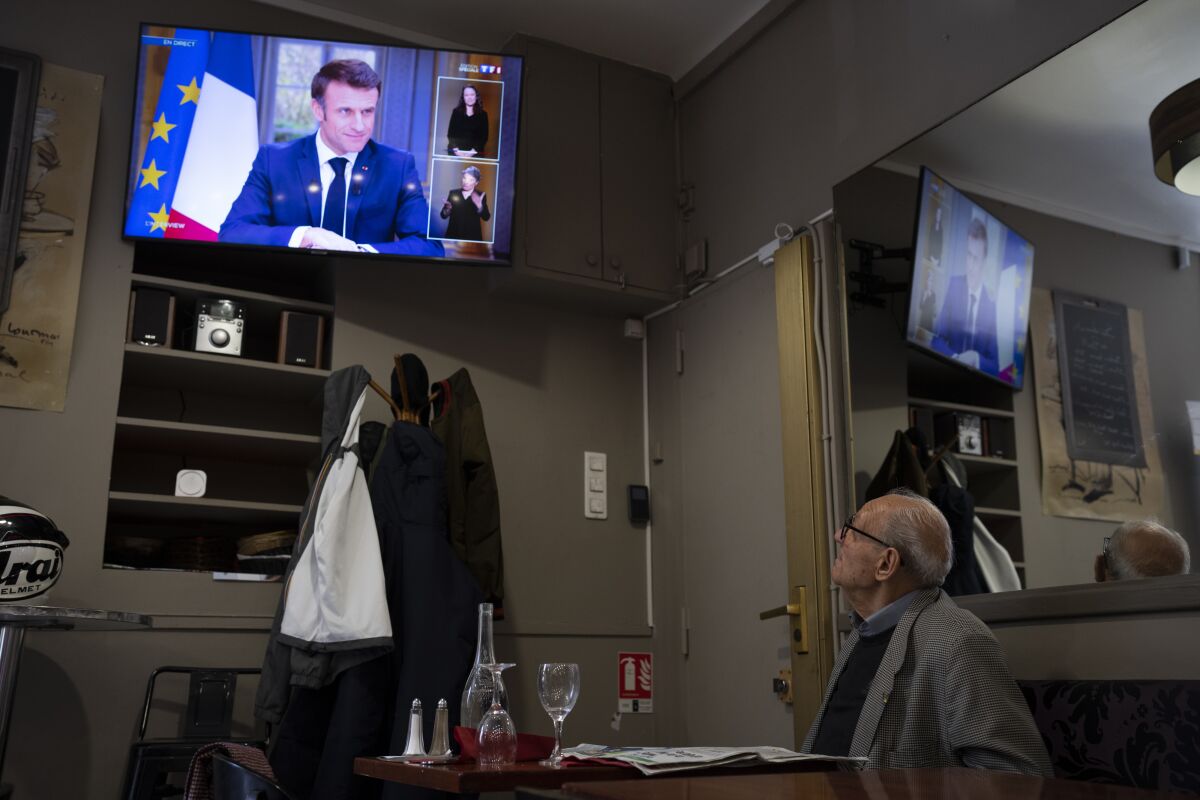 A man at a bar watches French President Emmanuel Macron speaking during an interview with journalists on television in Marseille, southern France, Wednesday, March 22, 2023. Macron said Wednesday that the pension bill that he pushed through without a vote in parliament needs to be implemented by the "end of the year.” (AP Photo/Daniel Cole)