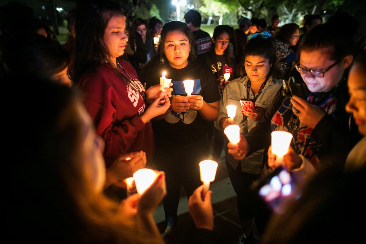Community members and students hold candles at a vigil for shooting victims.