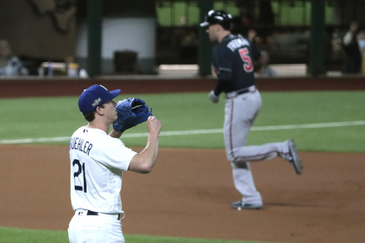 Walker Buehler tries not to look as Freddie Freeman rounds the bases on a first-inning homer.