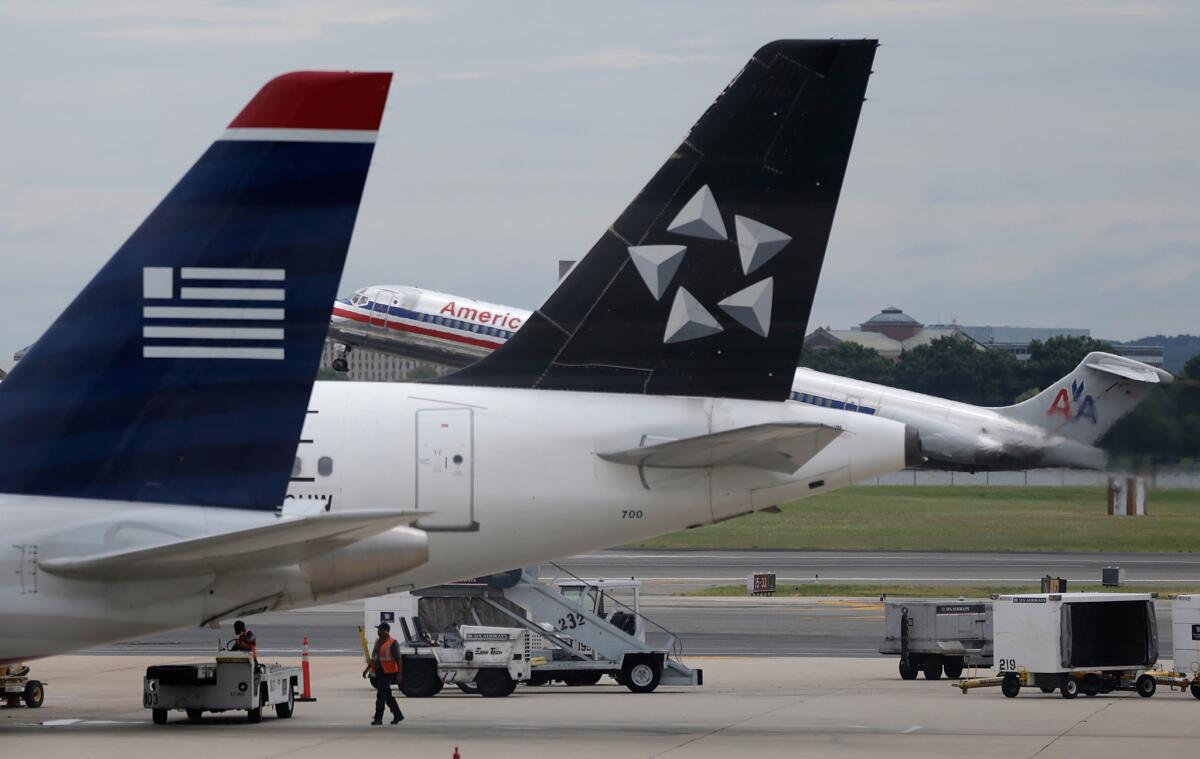 An American Airlines jet takes off behind US Airways jets at Ronald Reagan Washington National Airport.