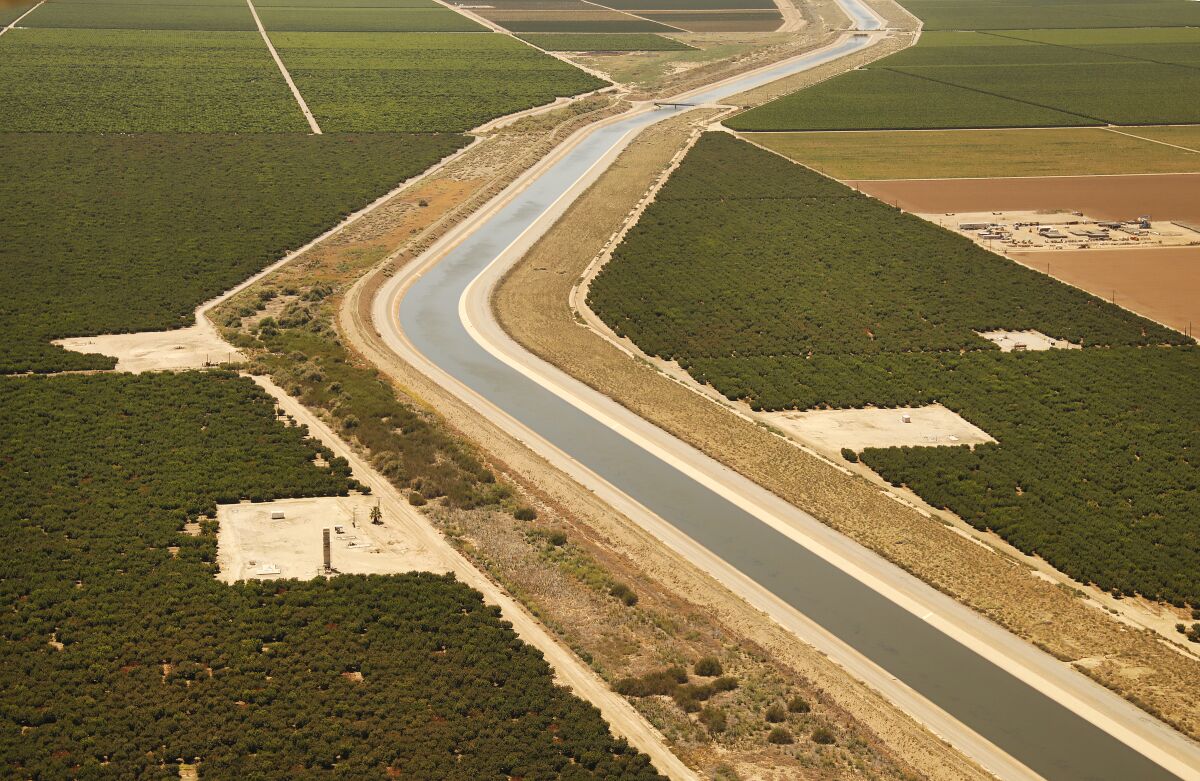 A bend in an aqueduct is seen from overhead as it runs through agricultural land