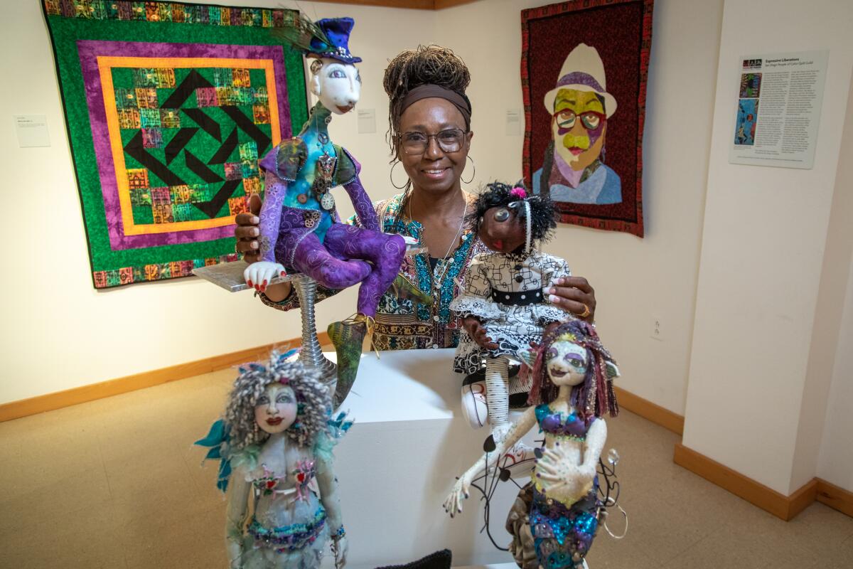 Textile artist Gloria Hazel poses with some of her fabric dolls featured in "Expressive Liberations" at Liberty Station. 