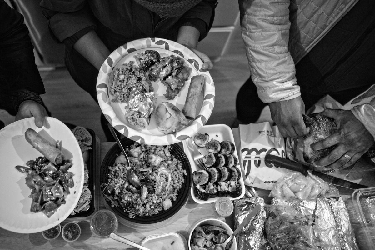 People fix plates from an overflowing potluck table