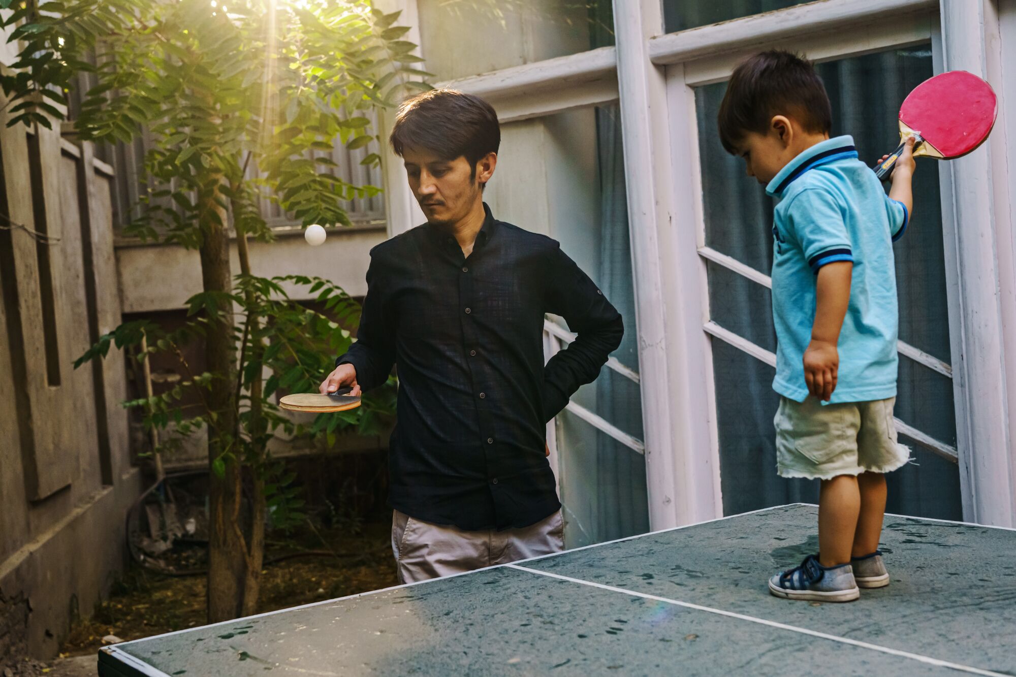 Man playing table tennis with his young son