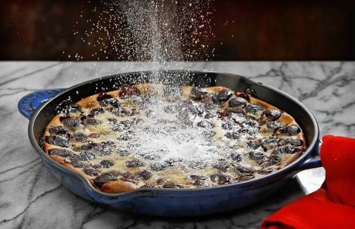 Powdered sugar is sprinkled atop a fresh cherry clafoutis.