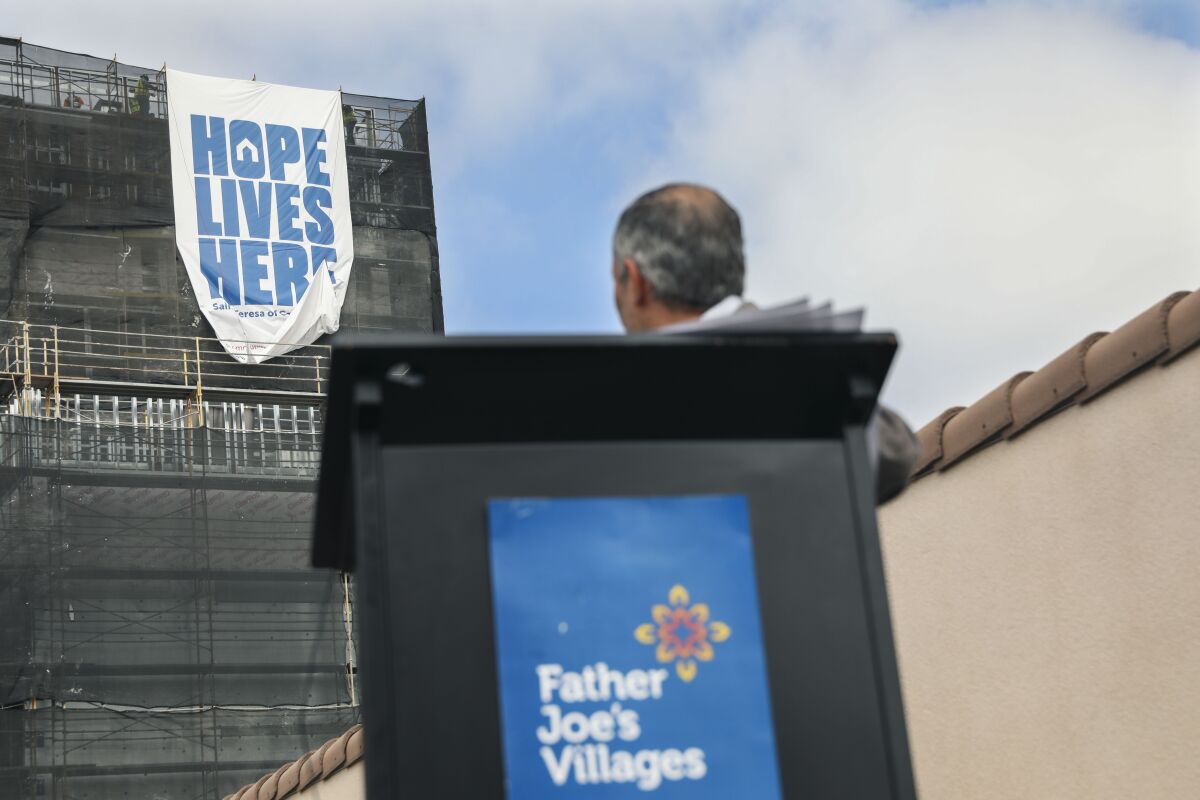 A photo from 2021 shows Father Joe's President Deacon Jim Vargas watch the unveiling of a banner reading "Hope Lives Here." 