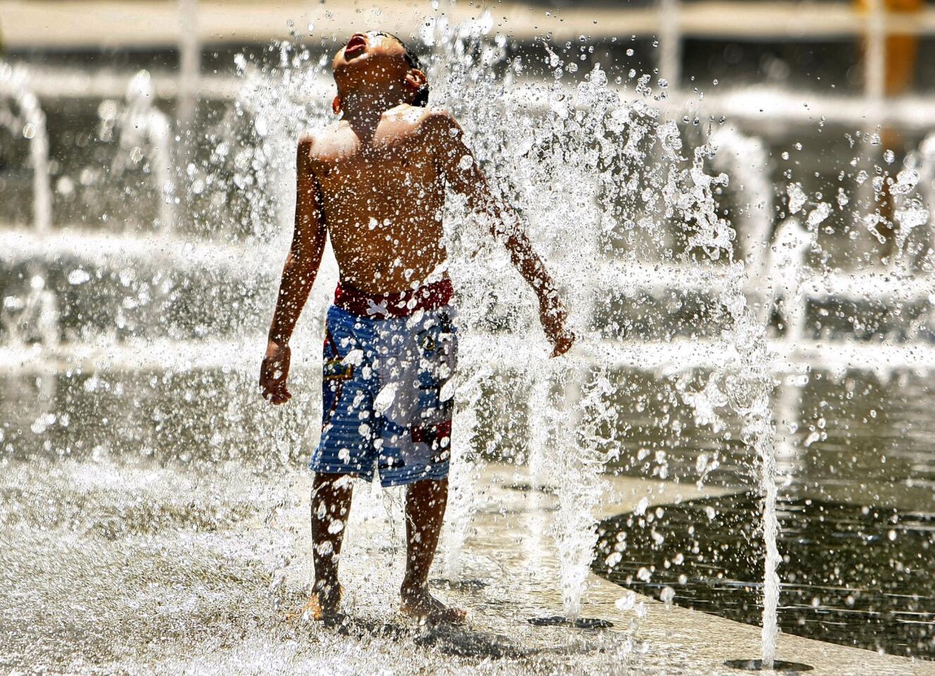 Four-year-old Adrian Martinez cools off with his mother and younger sister at the fountain in downtown L.A.'s Grand Park. The temperature reached 101 degrees, tying the city's record for the date set in 1970.
