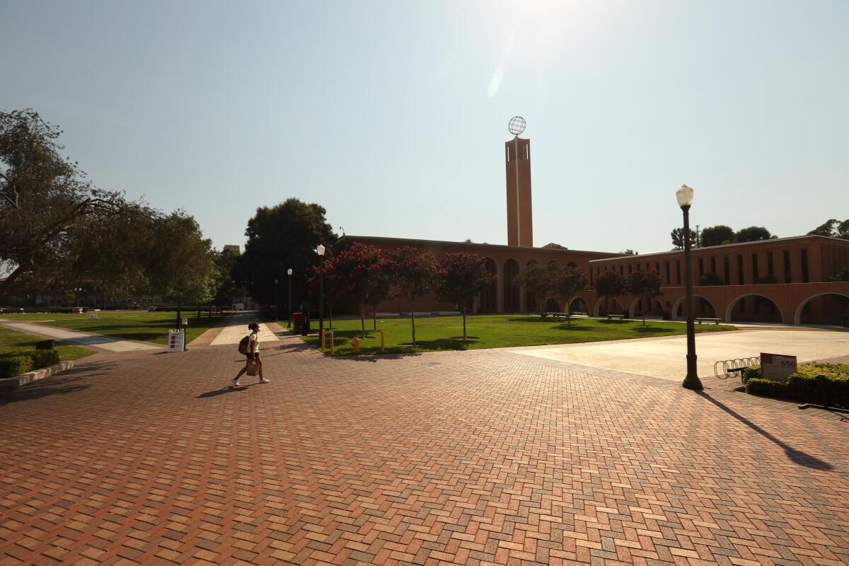 A lone student walks across an empty section of the USC campus.