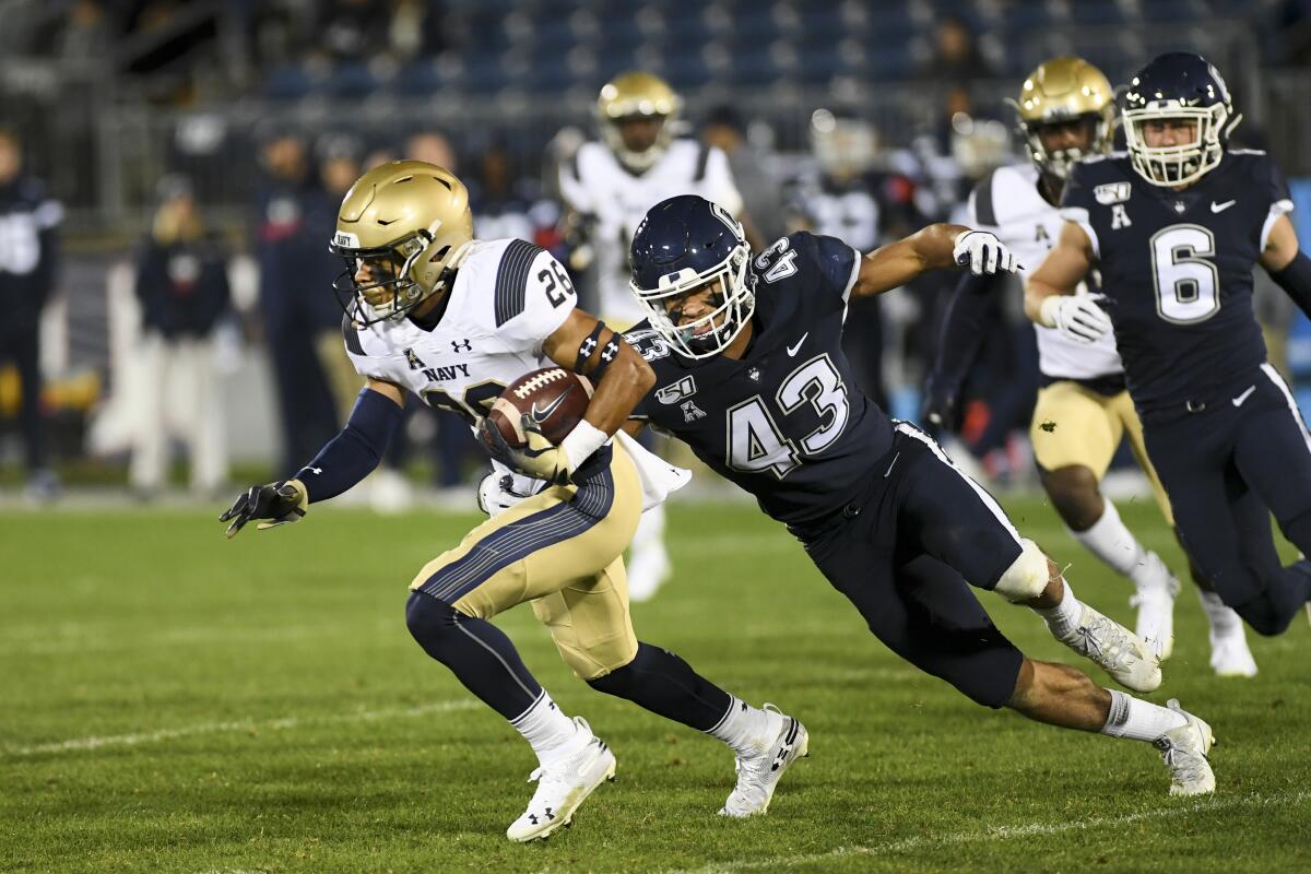 Navy wide receiver Garrett Winn (26) is chased down by Connecticut linebacker Jackson Mitchell during the Midshipmen's 56-10 victory on Friday.