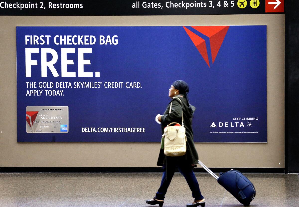 File photo of traveler walking past Delta credit card sign.