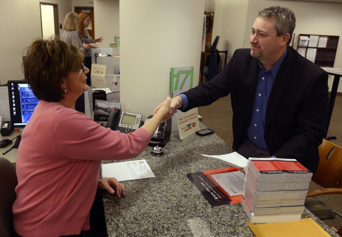 Shawn Phillips, right, owner of Strainwise marijuana stores, shakes hands with Jennifer Scott of the Denver Excise and License office after receiving his license to legally sell marijuana in the city.