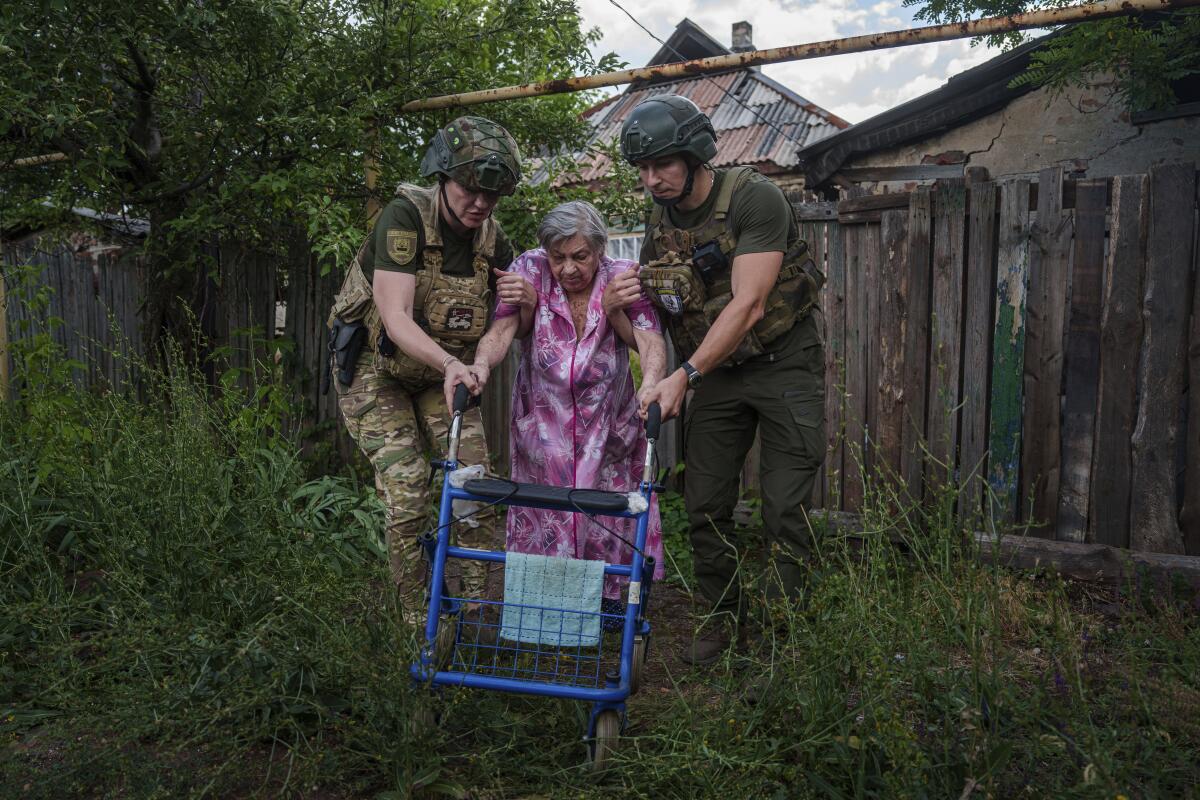 Police officers of the White Angels unit help an elderly woman walk in Toretsk, Donetsk region, Ukraine.