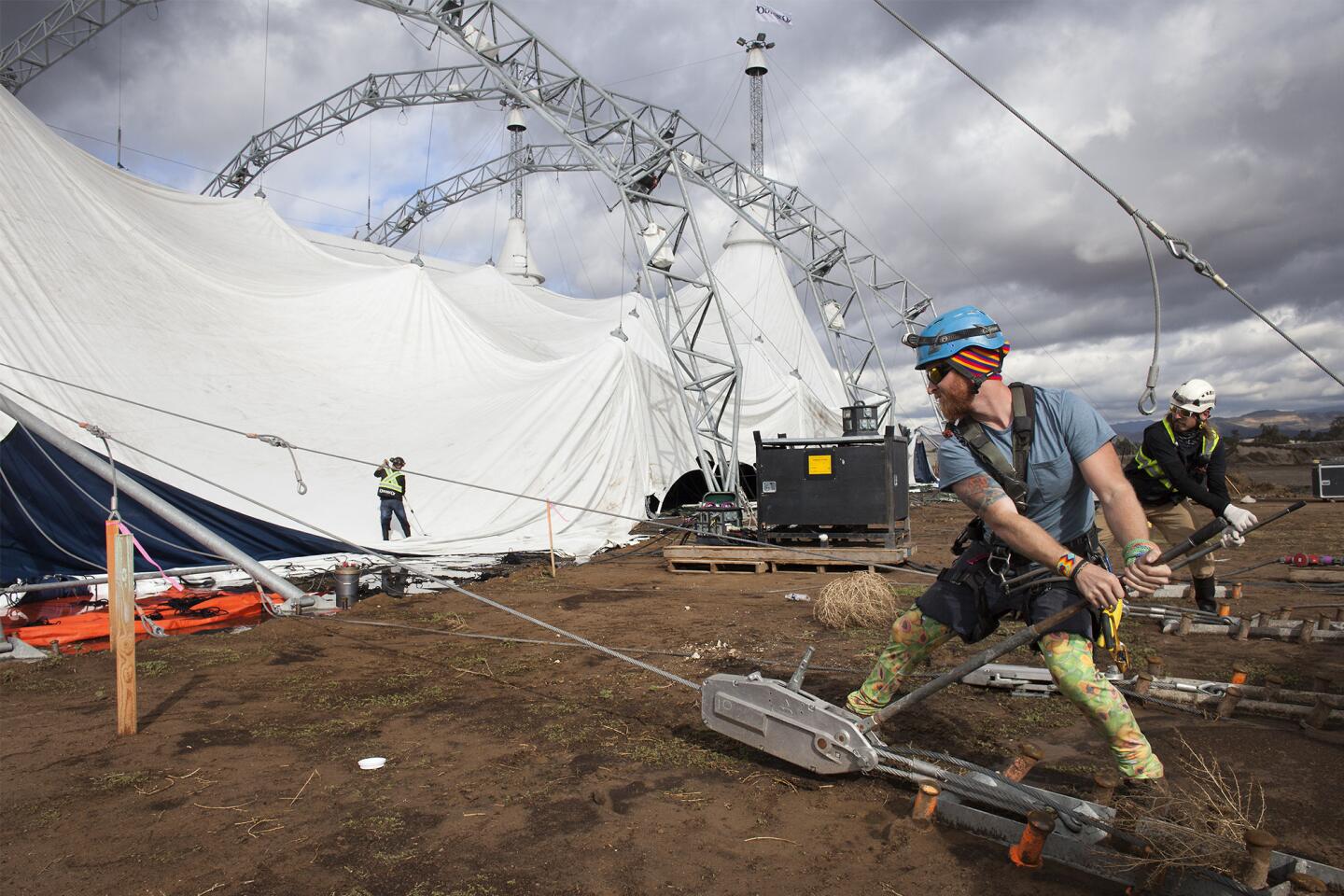 Crew members Max Arcand, second from right, and Kevin Rienks, far right, work on raising the world's largest tent in preparation for Orange County's debut of "Odysseo," by Cavalia, in Irvine on Thursday.