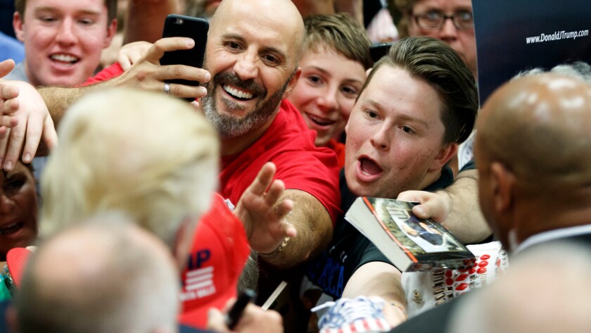 Donald Trump, a self-professed germophobe, signs autographs for fans at a campaign rally in Colorado Springs, Colo. on July 29.