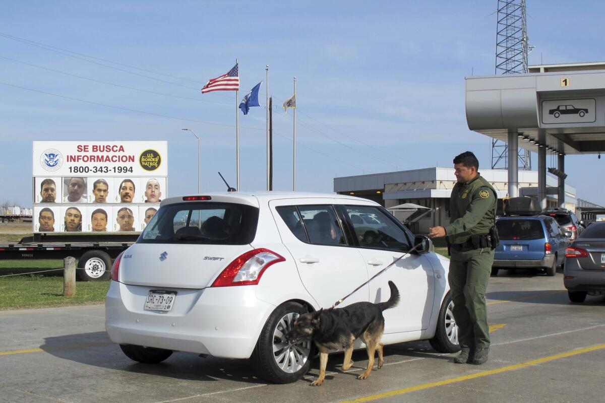 Un agente de la Patrulla Fronteriza utiliza un perro para inspeccionar un automóvil que espera pasar por el puesto de control de vehículos Laredo Norte en Laredo, Texas, el viernes 2 de febrero de 2018.