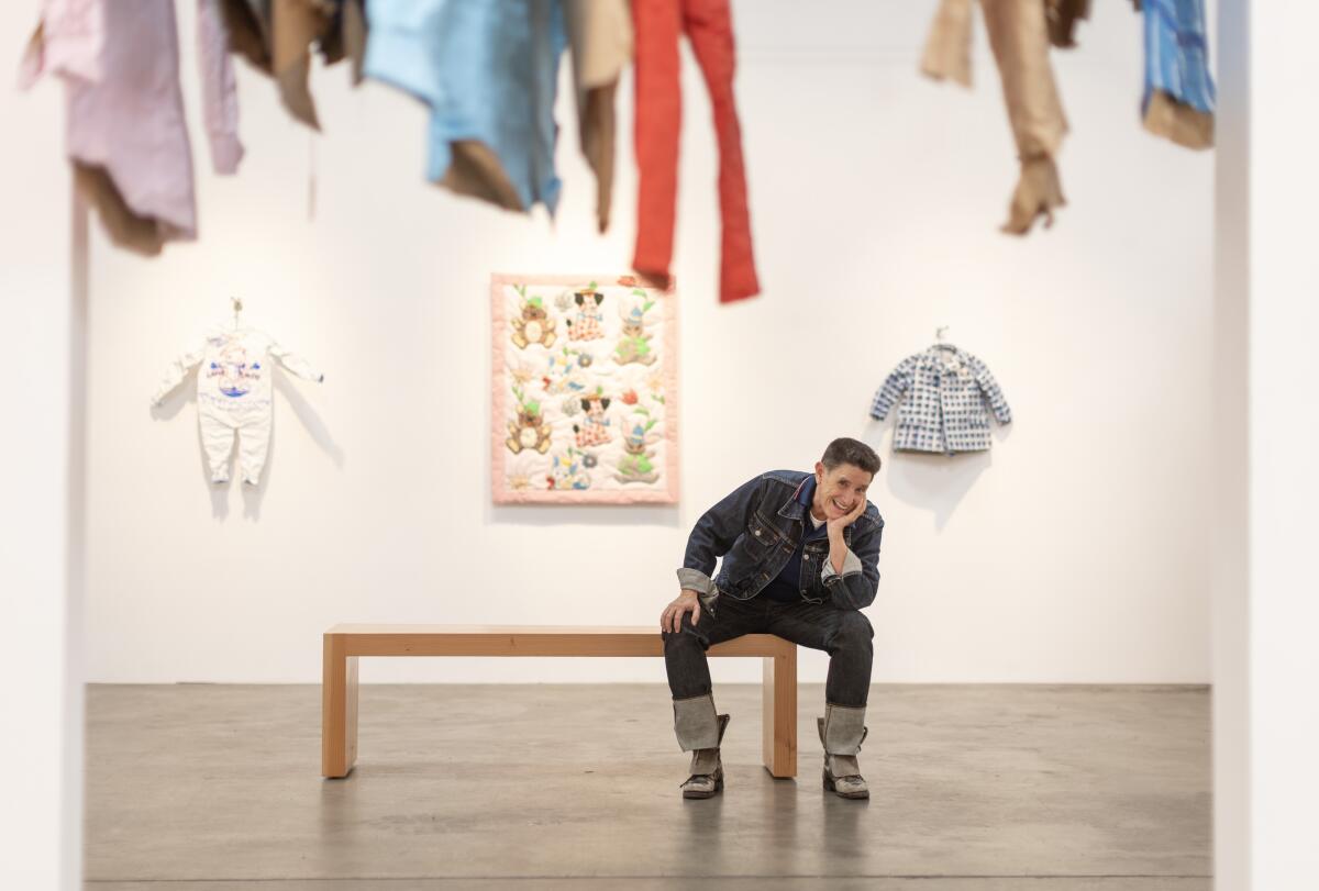 Phranc, wearing jeans and a leather jacket and her trademark flat top haircut, poses amid works made from cardboard.