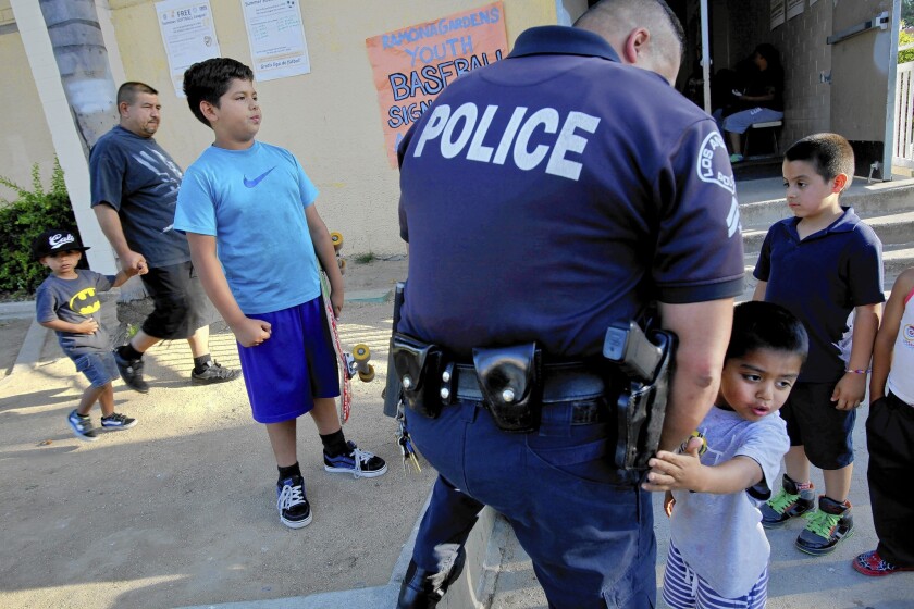 More than 20 years after a firebombing in Ramona Gardens drove black families from the Boyle Heights housing project, another attack threatens to erase the area's progress. LAPD Officer Clem Toscano entertains kids during a community meeting Wednesday.