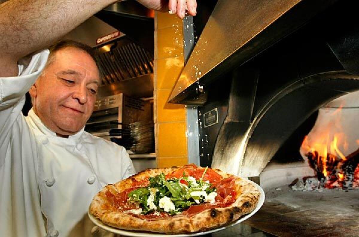 Il Dolce owner Roberto Bigne finishes off a prosciutto and arugula pizza from the oven.