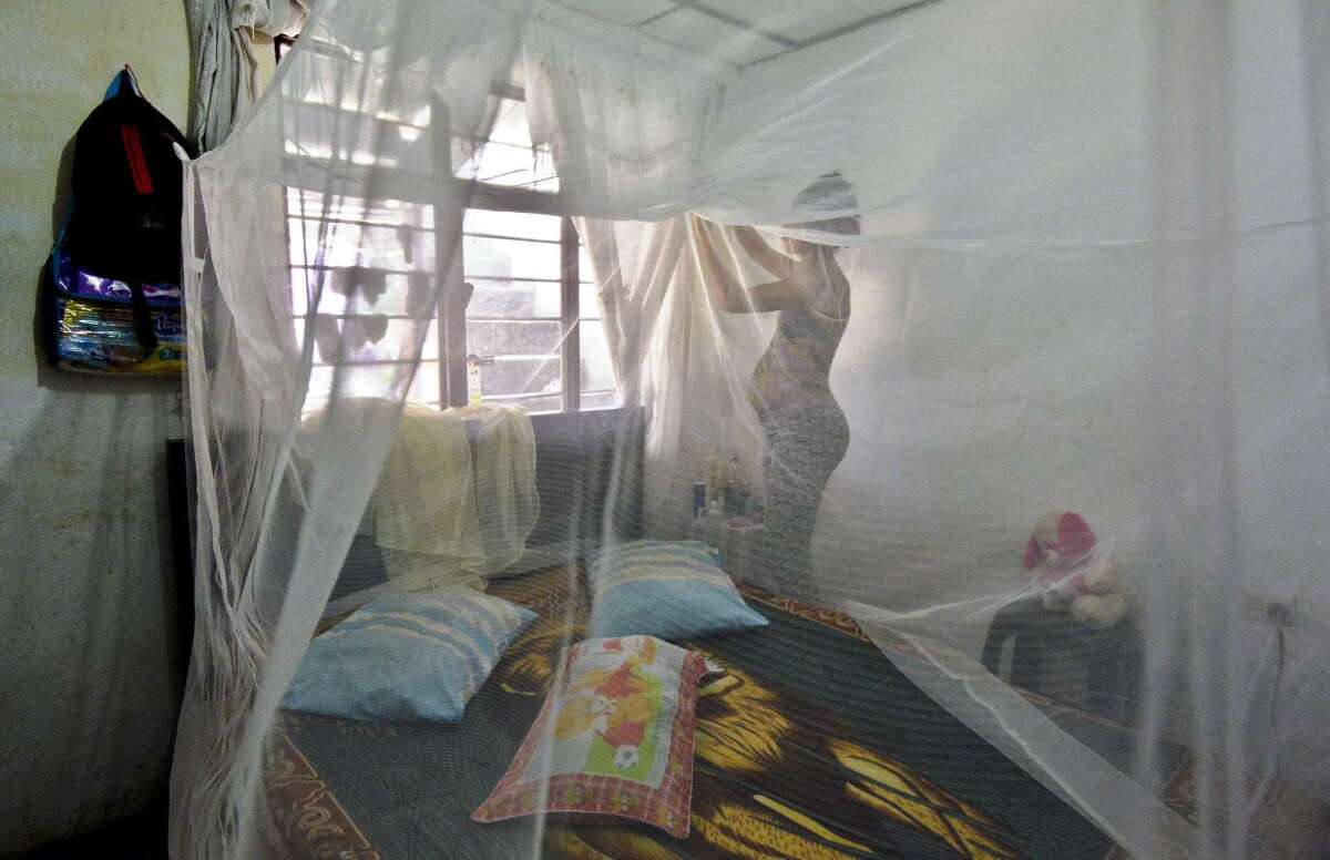 A woman who is seven months pregnant installs a mosquito net over her bed in Cali, Colombia on Feb. 17.
