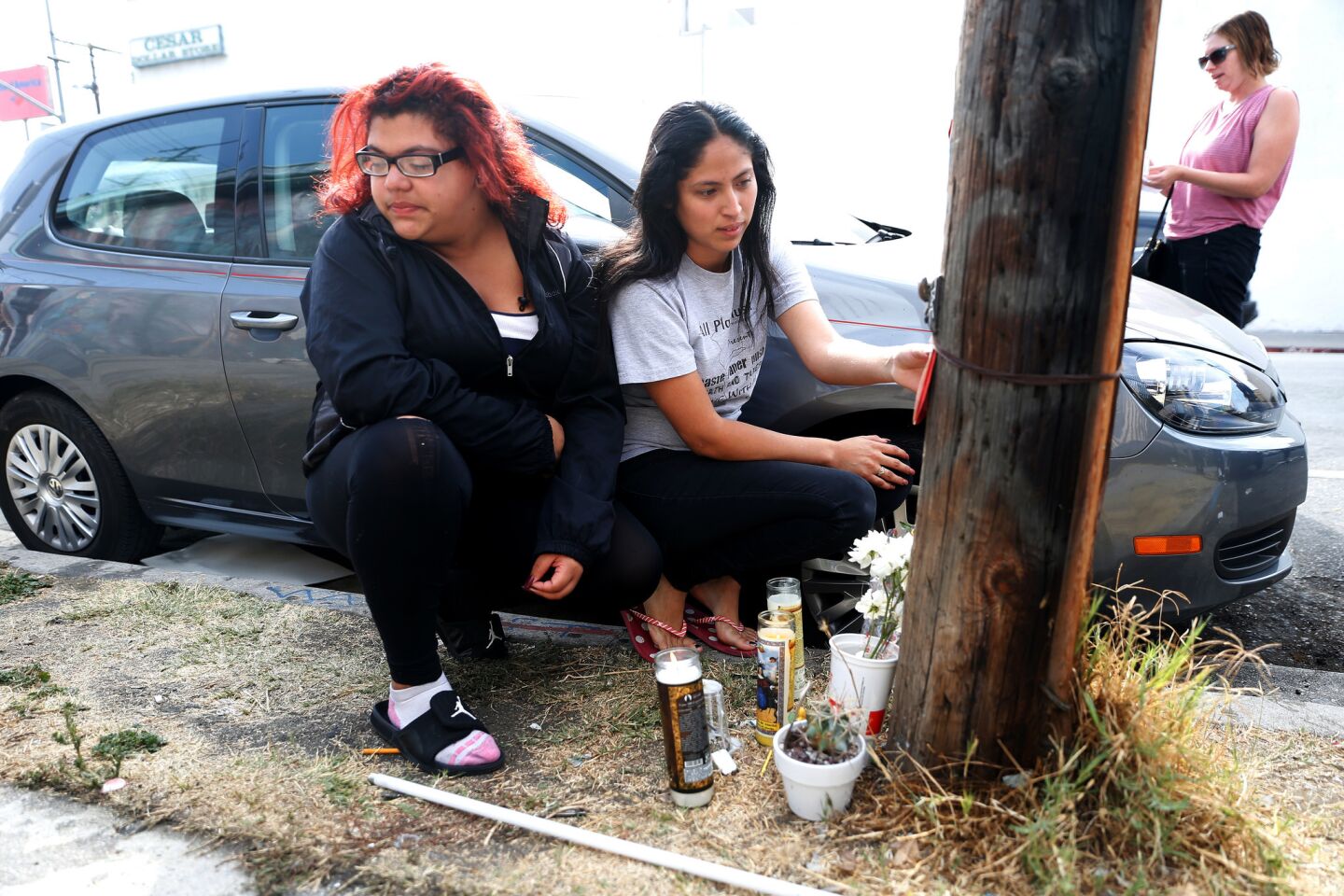 Shelsea Garcia, 16, left, and Gemma Martinez pay respects to friend Jesse Romero at a makeshift shrine set up along the 200 block of North Breed Street in Boyle Heights.