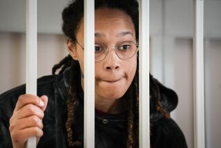 WNBA star Brittney Griner speaks to her lawyers while standing in a cage in a Russian court room