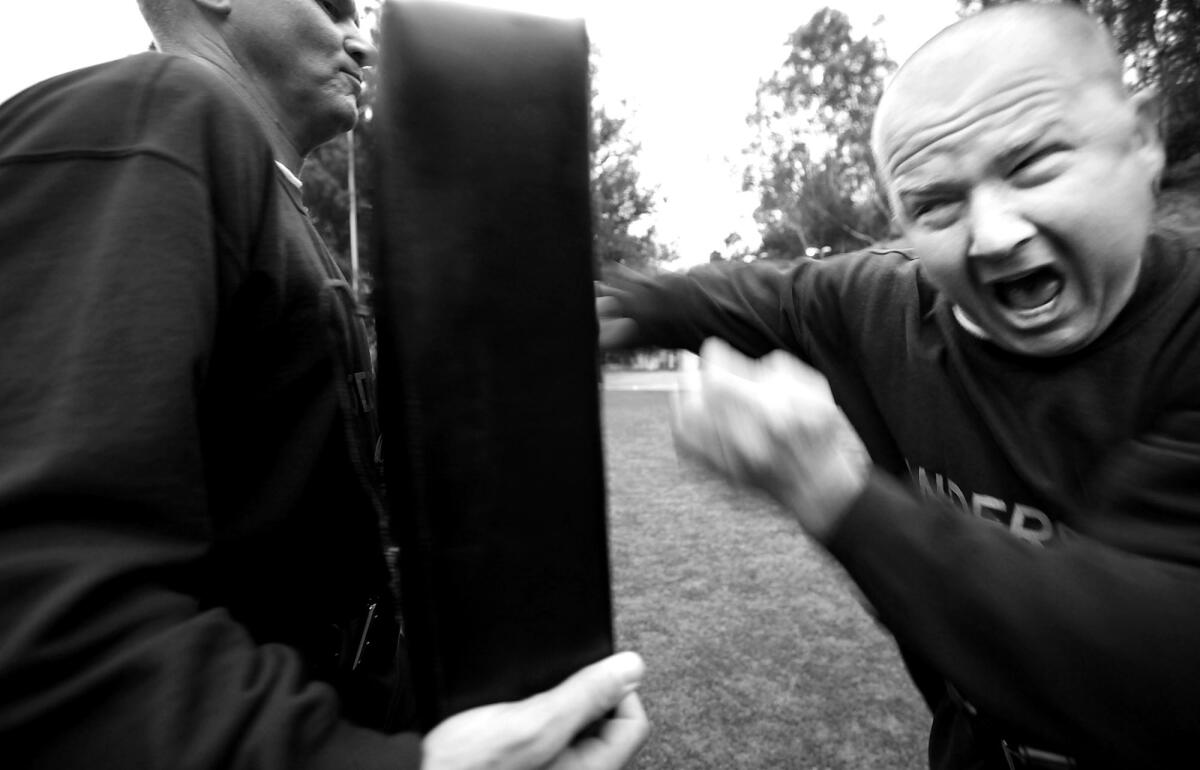 Recruit Jerry Todd holds a large pad as fellow recruit Ed Anderson throws punches.