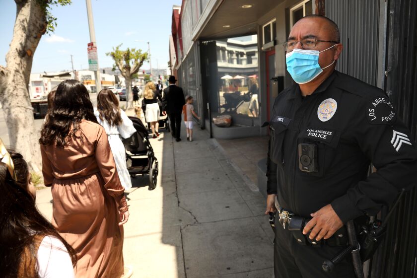 LOS ANGELES, CA - MAY 22, 2021 - - L.A.P.D. Sgt. Kenneth Price, a Senior Lead Supervisor, keeps a watchful eye over members of the Jewish community heading to Temple along La Brea Blvd. in the Fairfax District on May 22. 2021. Members of the Jewish community are concerned over the recent attacks this week to Jewish residents in Los Angeles amid Israeli-Palestinian violence in the Middle East. (Genaro Molina / Los Angeles Times)