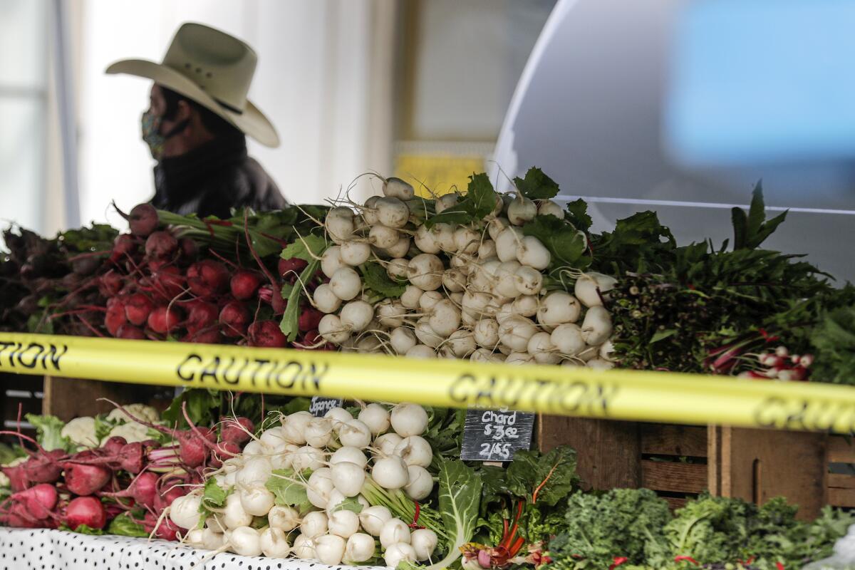 Farmers and their produce are separated by barricade tape at the Santa Monica Farmers Market.