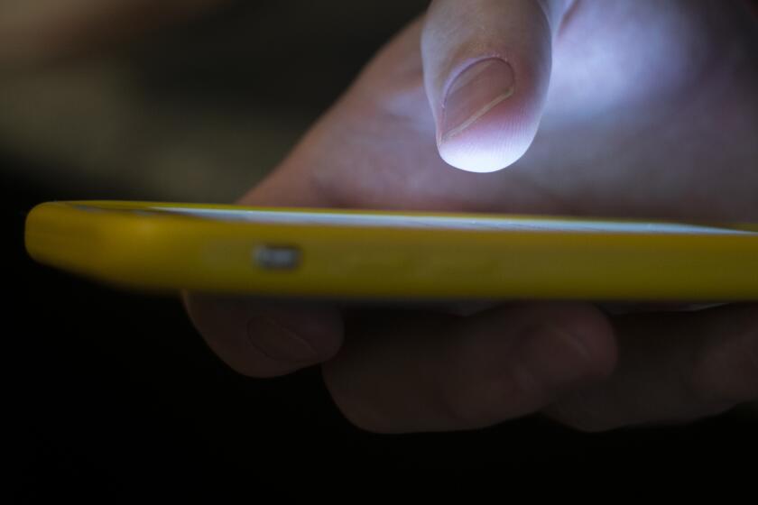 FILE - A man uses a cell phone in New Orleans on Aug. 11, 2019. A recent uptick in scams targeting older adults has seniors wondering who’s really calling them. As the most common type of reported Social Security scam, imposters fool beneficiaries into thinking they are providing information to the agency. (AP Photo/Jenny Kane, File)