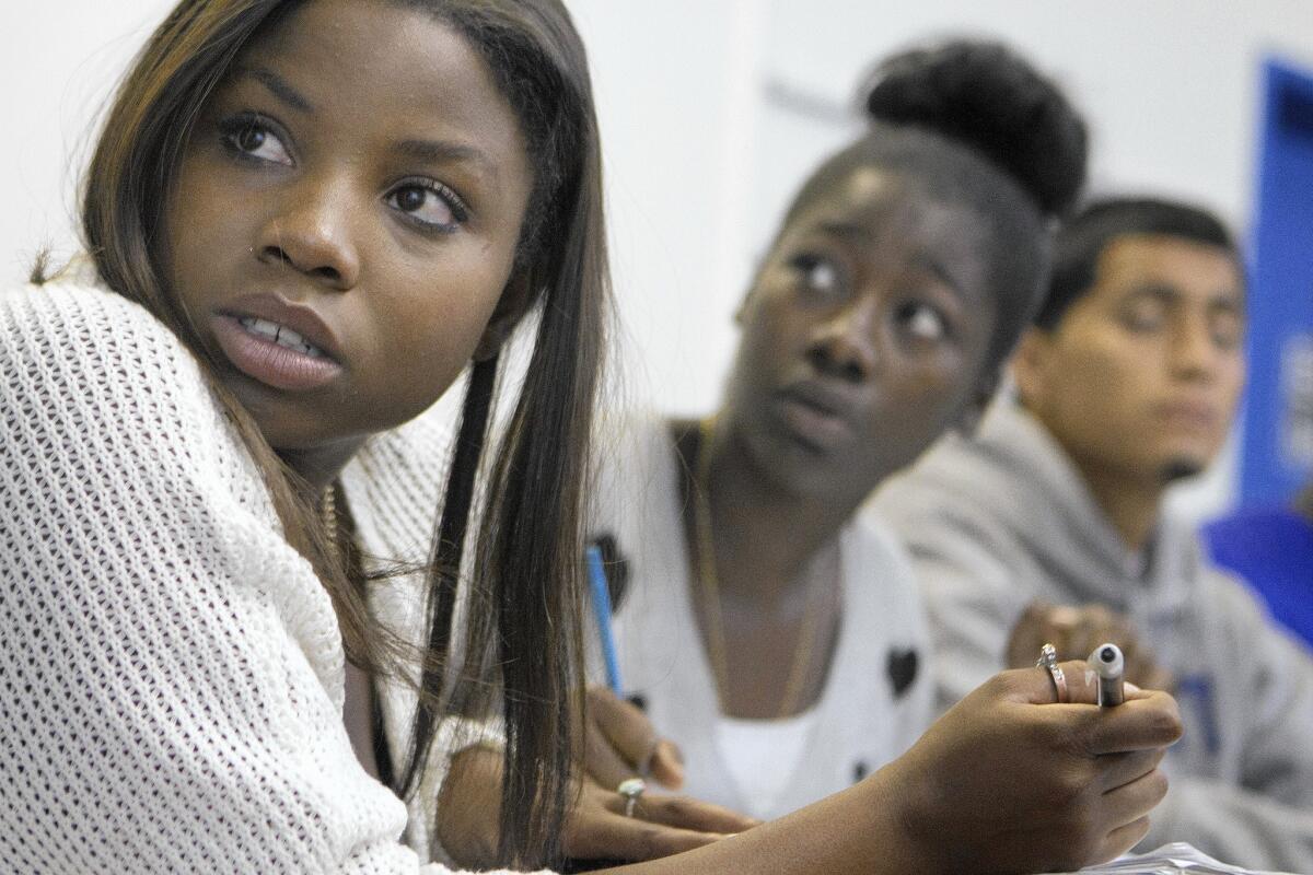 Renee Johnson, 20, from left, Robin Hall, 18, and Arnold Lopez, 18, take notes during a College Bridge class at the Brotherhood Crusade in Los Angeles.